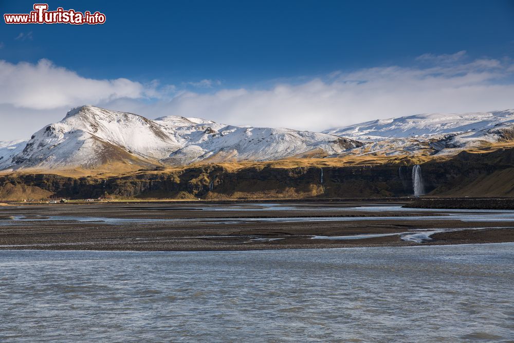 Immagine Il paesaggio autunnale del sud dell'Islanda con la cascata Seljalandsfoss e i vulcani innevati sullo sfondo