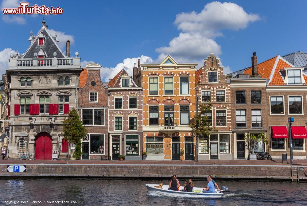 Immagine Case colorate affacciate su un canale di Haarlem, Olanda. In primo piano, una barca con persone e un cagnolino - © Marc Venema / Shutterstock.com