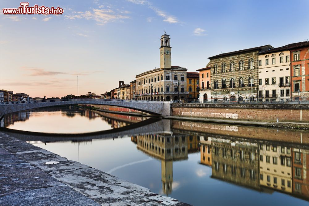 Immagine Case residenziali lungo il fiume Arno nel centro di Pisa, Toscana. Sullo sfondo la torre dell'orologio che si rispecchia nelle acque del fiume.