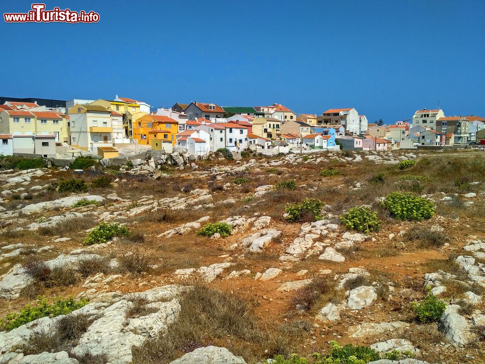 Immagine Case variopinte nei pressi delle rocce sulla costa oceanica di Peniche, Portogallo. Questa bella località portoghese rappresenta uno dei maggiori porti pescherecci del paese oltre che un grande centro di attività marittime e turistiche.