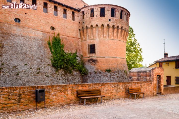 Immagine La Rocca Sforzesca ha forma esagonale con perimetro di circa 200 metri e si presenta sul lato frontale con due torrioni circolari: il più grande, detto il "Torresino", è posto nei pressi dell'ingresso ed ha un diametro di 16 metri, l'altro noto anche come dei "Bolognesi" ha invece perimetro di circa 11 metri. Al castello si accede transitando su un ponticello, un tempo mobile, a fianco del "Torresino", e dopo aver superato un portone d'ingresso in ferro ci si trova in un cortile su cui si affacciano sia l'entrata della rocca che quella dell'enoteca regionale dell'Emilia Romagna ospitata nei sotterranei - © GoneWithTheWind / Shutterstock.com