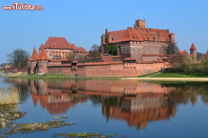 Immagine Il riflesso sul fiume Nogat del Castello di Malbork: dal 1997 il castello è iscritto nella lista dei siti Patrimonio dell'Umanità dell'UNESCO, e ammirandolo in tutto il suo splendore anche da fuori, sulla riva opposta del fiume Nogat, non si fatica certamente a capirne il motivo.