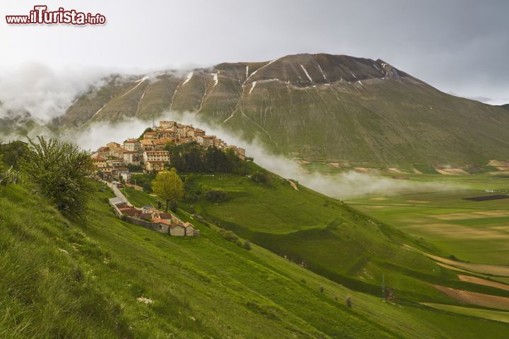 Immagine Castelluccio di Norcia fotografata dall'alto, prima del terremoto del 2016. A fare da cornice al centro abitato i Monti Sibillini con una leggera nebbia che ne sottolinea ancora di più il fascino - © Paul_Christener / Shutterstock.com