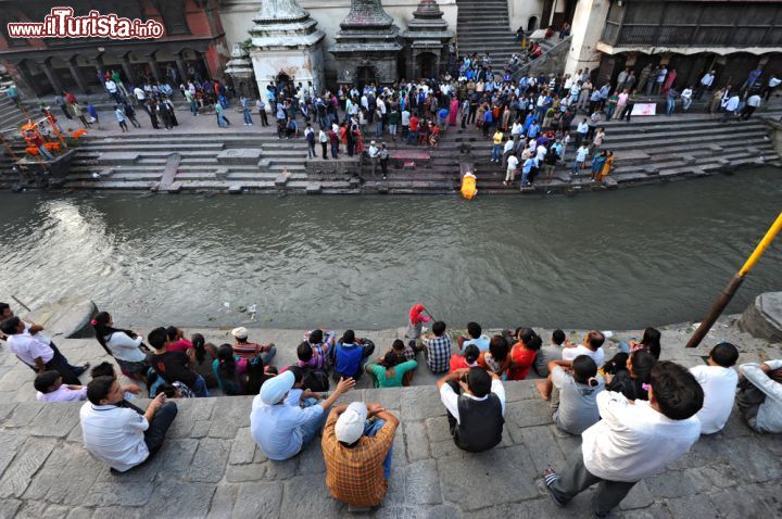 Immagine Cerimonia di cremazione lungo il fiume Bagmati a Kathmandu, Nepal. Fedeli durante la cerimonia funebre che si svolge quotidianamente con i corpi dei morti cremati sulle pire prima della dispersione delle ceneri nel Bagmati. Il tempio di Pashupatinath è uno dei luoghi più popolari per i turisti - © Hung Chung Chih / Shutterstock.com