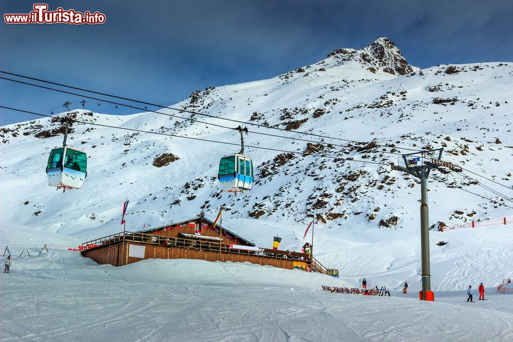Immagine Chalet di legno e piste da sci con la funivia sulle Alpi francesi di Les Menuires.