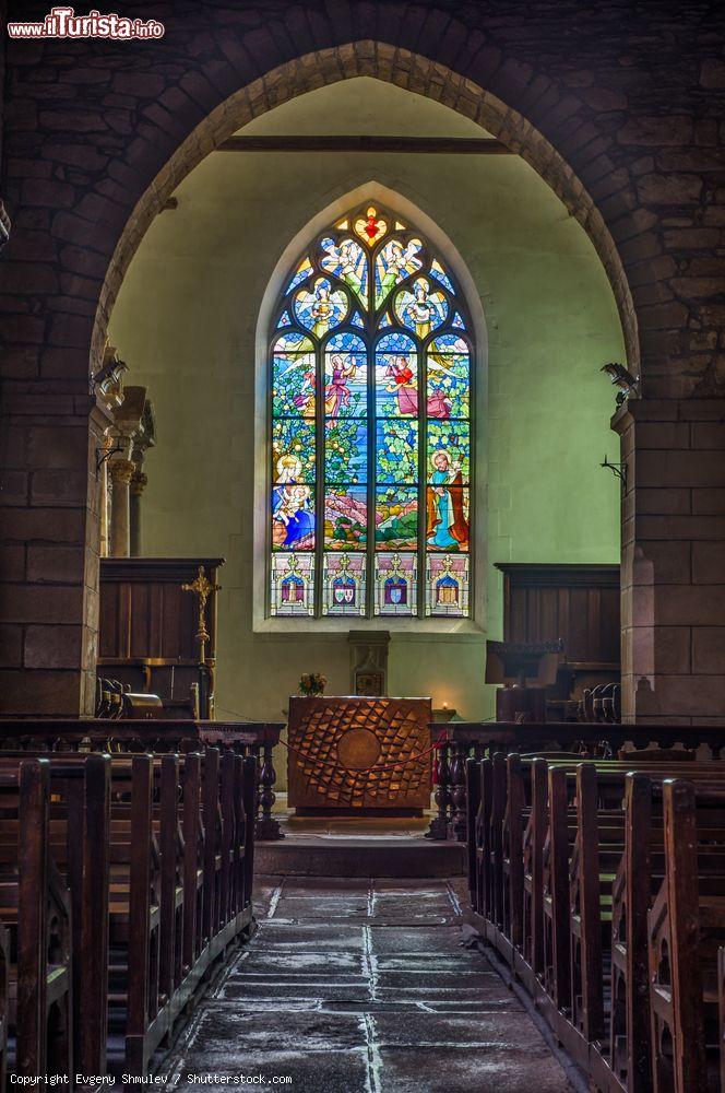 Immagine Chiesa a Rochefort-en-Terre in Francia. La Chiesa di Notre-Dame-de-la-Tronchaye, edificio religioso del XII secolo che, posto su un pendio sotto la città - si specchia nella propria bellezza tracciata con vellutato ardore da una facciata gotica accostata al fiancheggiante campanile romanico a pianta quadrata. All’interno è conservato l’unico altare militare di Francia, mentre nel cimitero attiguo prende posto la Bible des Pauvres (la Bibbia dei Poveri), Calvario tessuto da incisioni nel granito raffiguranti stazioni della Passione e Ascensione di Cristo: qui si insegnavano i dettami della Bibbia agli analfabeti, che erano il più delle volte poveri cristiani appartenenti al rango più basso della scala sociale. - © Evgeny Shmulev / Shutterstock.com