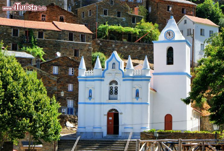 Immagine Chiesa di Nostra Signora da Conceicao a Piodao, Portogallo - Calce bianca e particolari azzurri per il principale edificio religioso della città portoghese: eretta dalla popolazione agli inizi del XIX° secolo utilizzando l'oro e il denaro di tutti, questa chiesa è dotata di singolari contrafforti cilindrici. Grazie al bianco della sua facciata, l'igreja matriz risalta fra le abitazioni in scisto del paese © Vector99 / Shutterstock.com