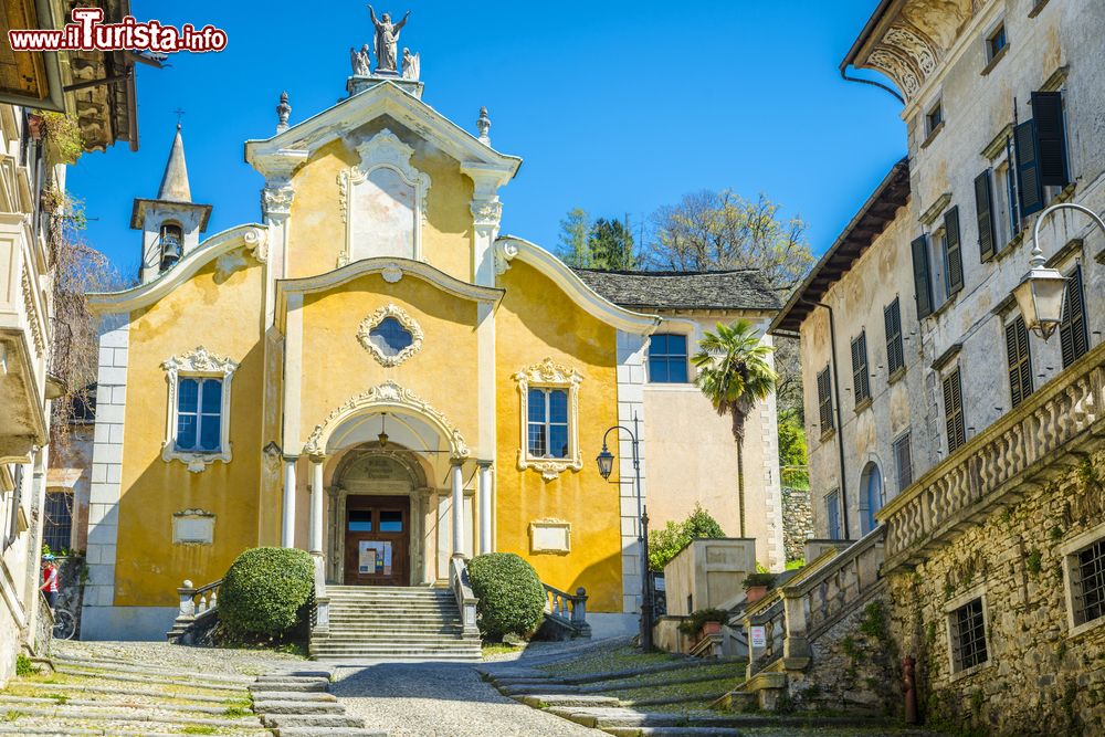 Immagine La chiesa di Santa Maria Assunta a Orta San Giulio, Piemonte, Italia. Sulla sommità della salita della Motta si erge questo bell'edificio religioso costruito per volere degli abitanti dopo la pestilenza del 1485. La facciata colorata è impreziosita dal portale in pietra che risale all'epoca della costruzione.