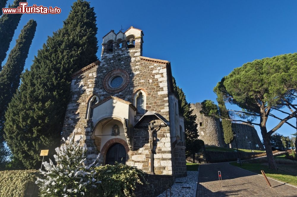 Immagine La chiesetta del Santo Spirito con l'ingresso al castello di Gorizia sullo sfondo, Friuli Venezia Giulia, Italia. Sorto per volere della famiglia toscana dei Rabatta, questo edificio religioso fu costruito in stile gotico fra il 1398 e il 1414.