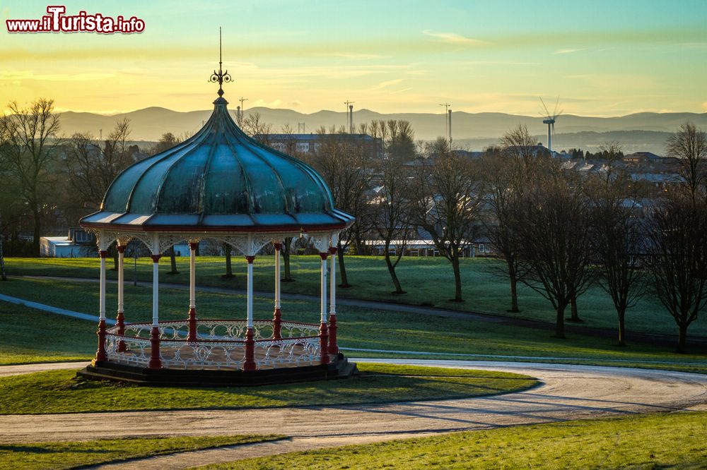 Immagine Un chiosco nel parco di Dunfermline, Scozia, UK. I colori dell'alba con sullo sfondo le turbine eoliche e le torri Queensferry Crossing.