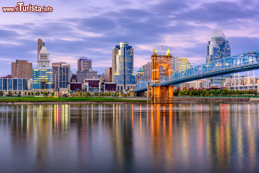 Immagine Cincinnati, Ohio, USA: skyline del centro e ponte sul fiume al crepuscolo. La città sorge nella parte sud occidentale dello stato in un'area urbana di discrete dimensioni.