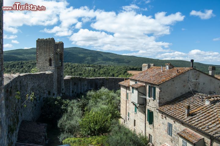 Immagine Città turrita di Monteriggioni, Toscana (Italia) - Quando la si guarda dal basso si ha la sensazione di sentirsi piccoli, vista la sua conformazione urbana e le sue maestosi torri. La caratteristica piuttosto curiosa è che avviene lo stesso procedimento anche quando la si guarda dall'alto, come nel caso di questa immagine. Con un cielo meraviglioso che abbraccia i vigneti nel circondario del borgo e il profilo delle mura, la sensazione visiva è di gran lungo superba - © kozer / Shutterstock.com