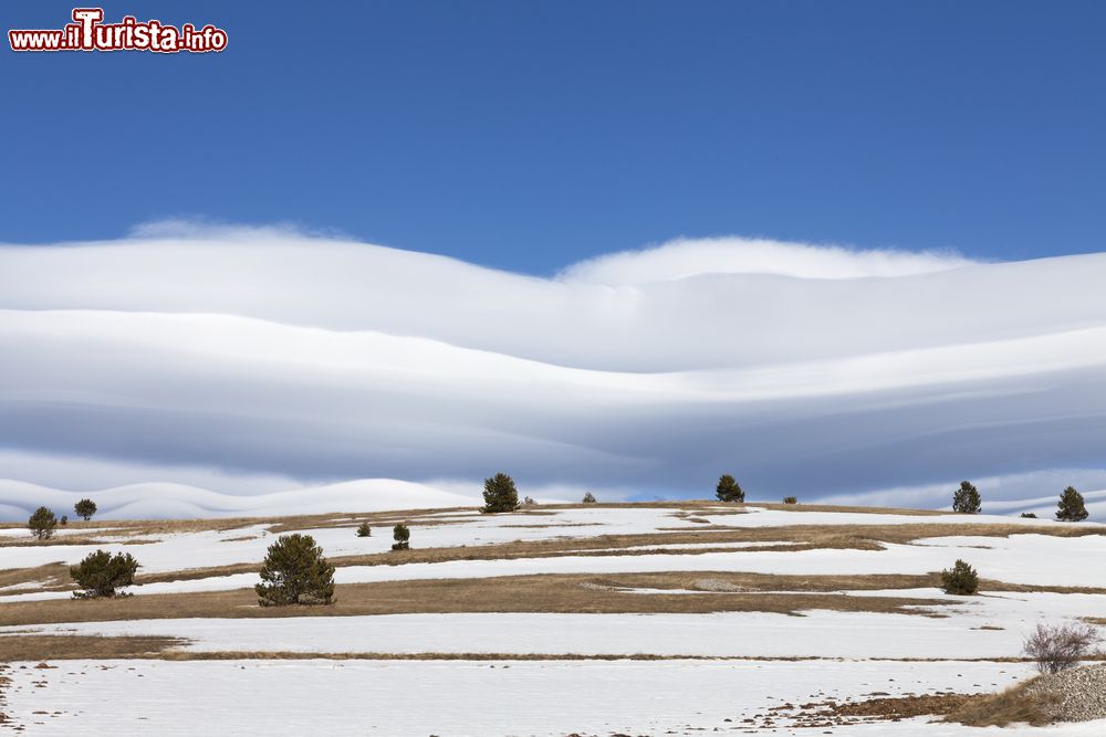 Immagine Nuvole pittoresche nel cielo blu e una deserta collina innevata a Santo Stefano di Sessanio, L'Aquila, Abruzzo. Questo splendido paesaggio si può ammirare nei pressi del Gran Sasso.