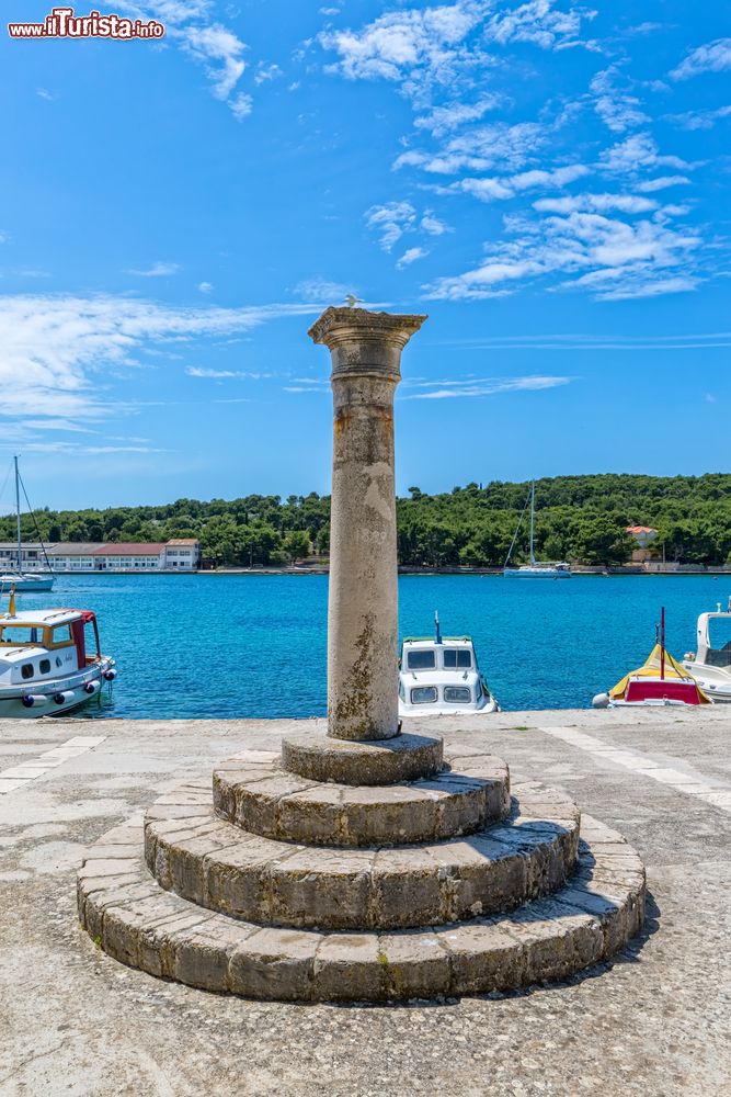 Immagine Colonna e basamento rotondo in pietra al porto di Prvic Luka in estate, isola di Prvic, Croazia.