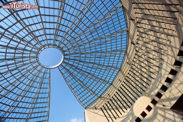 Immagine La cupola del Museo Mart a Rovereto, Trentino. L'edificio che ospita il museo d'arte moderna e contemporanea è stato progettato dall'architetto Mario Botta e dall'ingegnere Giulio Andreolli che si sono ispirati a modelli classici per le forme dedicando grande attenzione alle soluzioni tecniche. Di particolare interesse è la cupola radiale in acciaio e plexiglas che presenta uno spicchio mancante grazie a soluzioni ingegneristiche complesse e all'avanguardia. Al di sotto della cupola si trova una piazza con al centro una fontana - © Natalia Macheda / Shutterstock.com