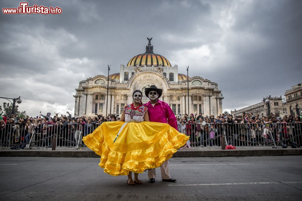 Immagine Uomo e donna travestiti da Catrina per celebrare la morte e i propri defunti durante la parata proposta in occasione del Giorno dei Morti. Sullo sfondo il Palazzo di Bellas Artes.