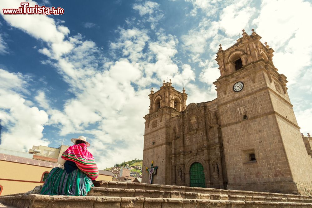 Immagine Una donna con la tradizionale keperina sulla schiena sui gradini della cattedrale di Puno, Perù.