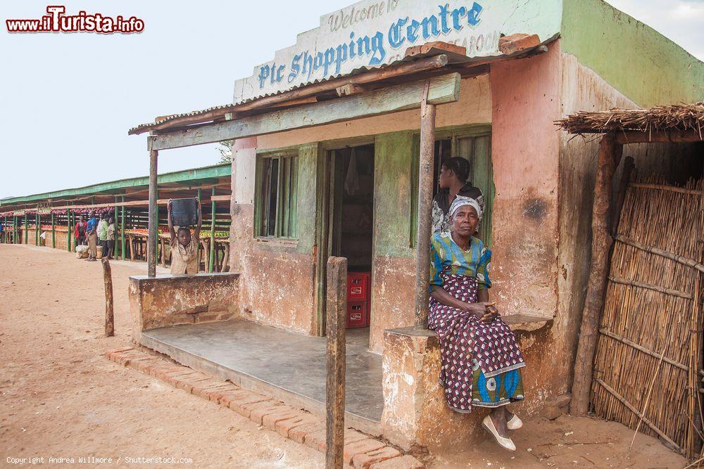 Immagine Una donna del Malawi con abiti tradizionali seduta davanti a una drogheria della città di Lilongwe - © Andrea Willmore / Shutterstock.com