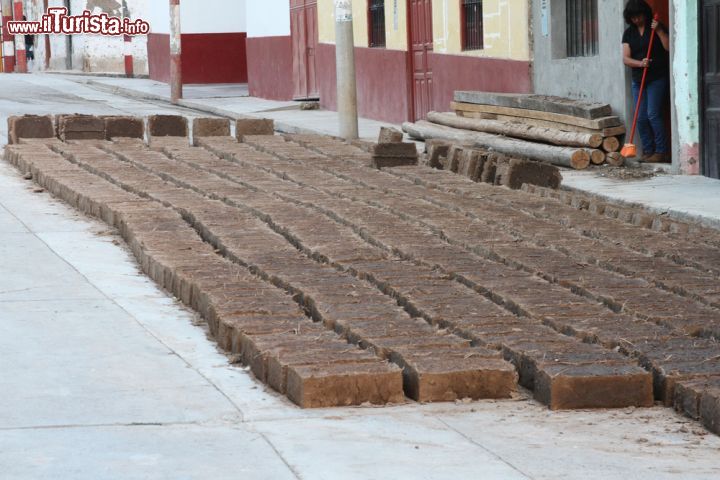 Immagine Una donna spazza il marciapiede su cui sono lasciati a essiccare mattoni di adobe a Magdalena, Perù. E' un impasto di argilla, sabbia e paglia quello utilizzato da molte popolazioni del Sudamerica per preparare i mattoni. Anche qui nei pressi di Cajamarca la tecnica utilizzata è la stessa - © Janmarie37 / Shutterstock.com
