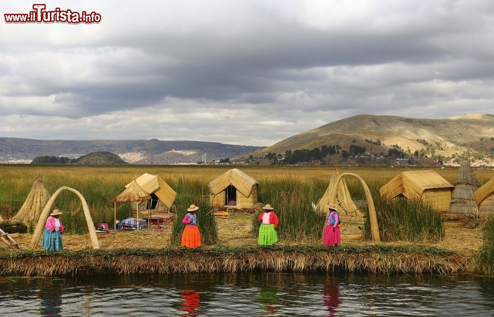 Immagine Donne in abiti tradizionali invitano i turisti a visitare le isole degli Uros sul lago Titicaca, Perù. Gli Uros sono una popolazione fuggita alle invasioni degli Inca. Sin da quell'epoca vivono su isole galleggianti costruite grazie alla totora, una particolare pianta che cresce abbondante nel lago Titicaca.