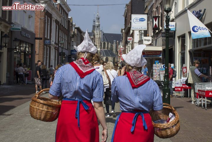 Immagine Donne in abito tradizionale olandese in una strada di Alkmaar - In questa città dell'Olanda nessuno viene meno alle tradizioni: dai portatori di formaggio ai mercati ai bambini, dai padri che indossano segni distintivi olandesi ai nonni, ma sono soprattutto le donne a continuare l'identità di costume, non rinunciando ad indossare il vestiario tipico della moda olandese che appartenne agli anni del passato - © Michela Garosi / www.thetravelover.com/it/