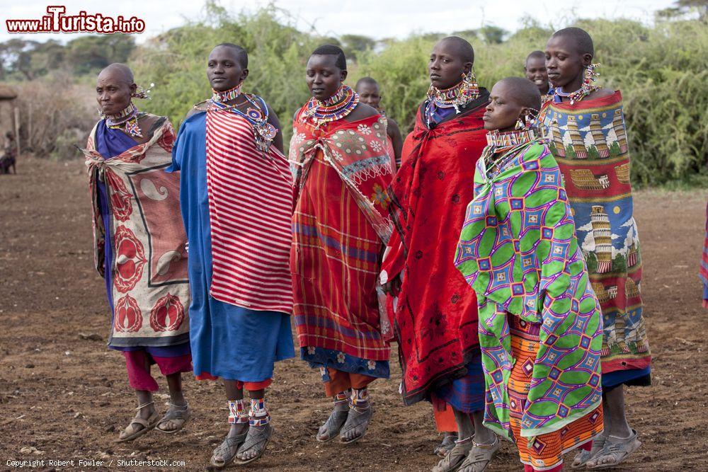 Immagine Donne Masai con abiti tradizionali durante una danza, Amboseli, Kenya. Questa popolazione veste con teli leggeri di cotone su cui poi viene poggiata la shuka, una coperta di cotone a quadri con colori predominanti rosso e nero - © Robert Fowler / Shutterstock.com