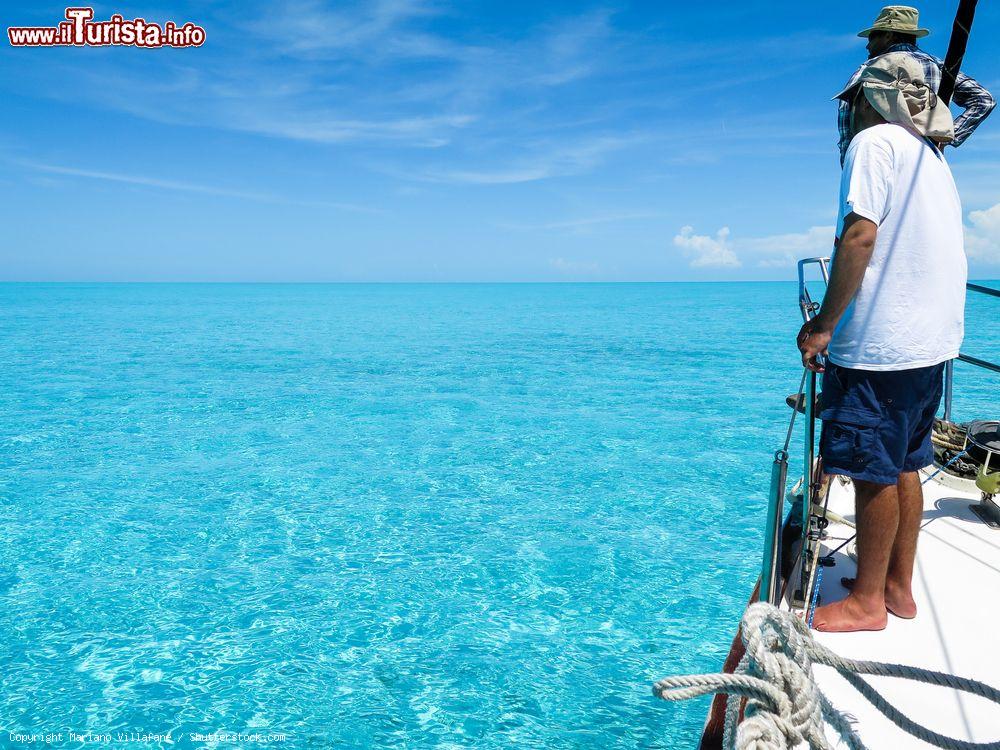 Immagine Due amici guardano l'orizzonte dalla prua di una barca a vela mentre attraversano il grande banco di sabbia delle isole Bimini, Bahamas - © Mariano Villafane / Shutterstock.com