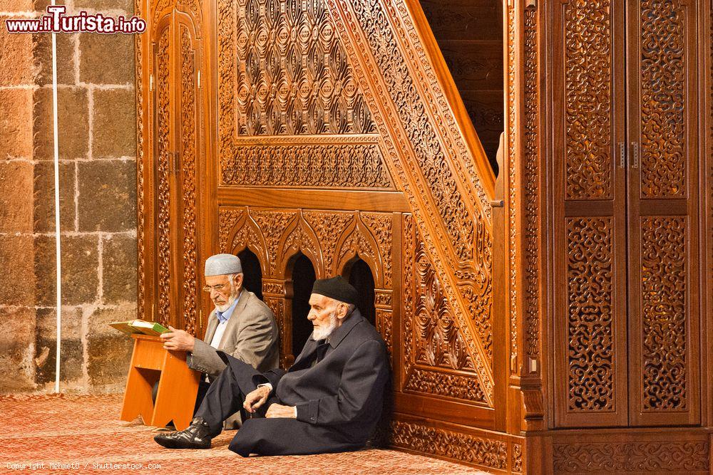 Immagine Due anziani musulmani seduti nella moschea di Ulu a Erzurum, Turchia. Uno dei due legge e prega con il Corano - © MehmetO / Shutterstock.com