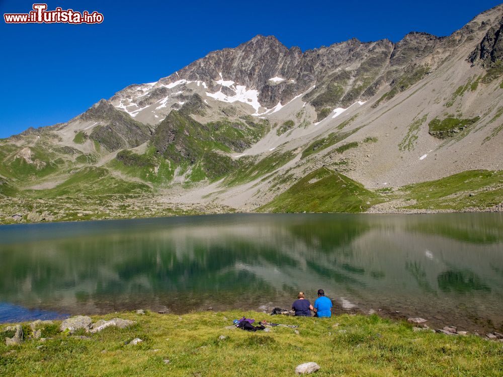 Immagine Due escurisonisti si riposano ai bordi di un lago dopo un trekking sulle montagne di Les Contamines, Francia.