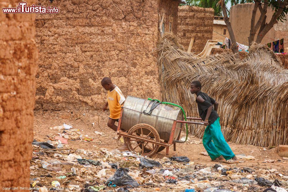 Immagine Due ragazzi spingono una botte d'acqua in un sobborgo di Ouagadougou, Burkina Faso. E' uno  dei metodi più utilizzati per distribuire acqua agli abitanti - © MattLphotography / Shutterstock.com