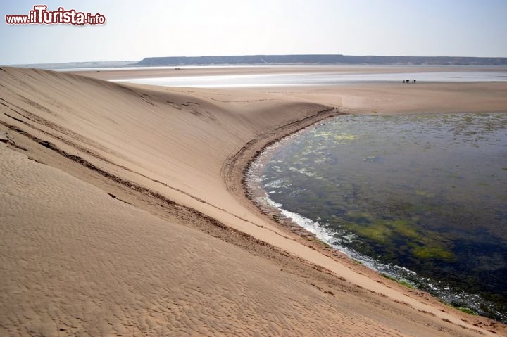 Immagine Dune Blanche: la duna si getta nelle acque della Baia di Dakhla in questo che è probabilmente il luogo più spettacolare della laguna. Molti kitesurfer, con l'alta marea, ne approfittano per fare altrettanto e lanciarsi in mare direttamente dall'alto della duna.