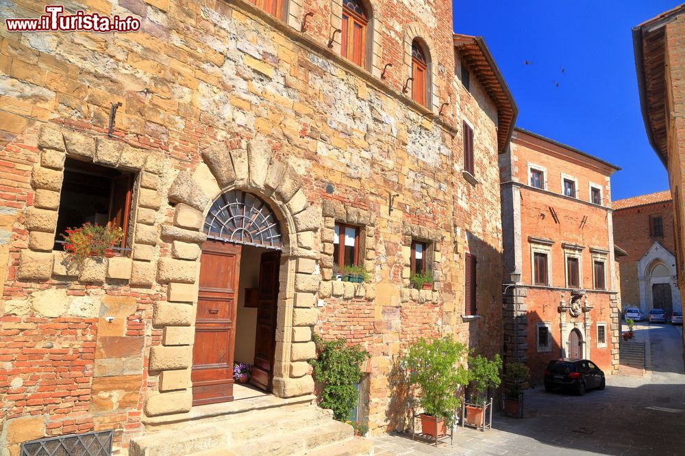 Immagine Edifici medievali in una strada soleggiata di Montepulciano, Toscana, Italia. La città è racchiusa da alte e imponenti mura.