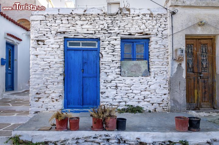 Immagine Facciata di una vecchia casa a Kythnos, Grecia. Pietra tinteggiata di bianco con porta e finestra azzurre per questa tradizionale abitazione dell'isola di Citno appartenente all'arcipelago delle Cicladi - © kokixx / Shutterstock.com