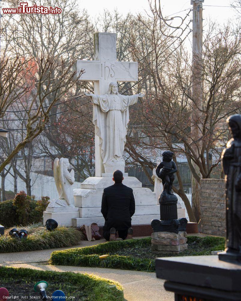 Immagine Un fan di Presley in preghiera di fronte alla tomba di famiglia nel Meditation Garden di Graceland, Memphis (Tennessee). Qui è sepolto Elvis Presley - © Juli Scalzi / Shutterstock.com