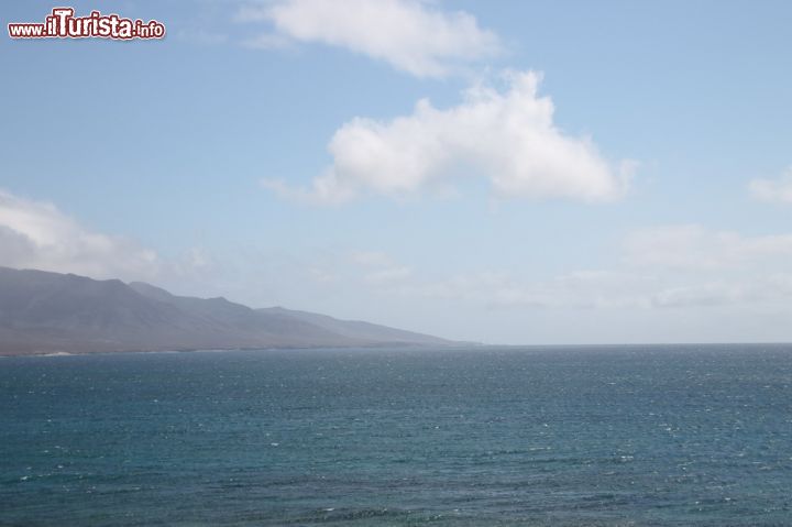 Immagine Il panorama di Faro de punta Jandia, Fuerteventura - Sì, i pendii di Morro Jable sono piuttosto ripidi come si può vedere dall'immagine. Il fatto che siano così a strapiombo sul mare e al tempo stesso così ordinati nella loro imperfezione, rende il quadro sublime. Nei giorni di cielo terso come in questa immagine, il mare poi sembra una coccarda che porta a domicilio un regalo visivo stupendo.