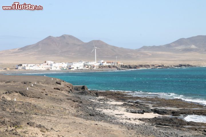 Immagine A sud di Fuerteventura, il Faro de punta Jandia in lontananza - Le scogliere piuttosto ripide ma anche le più tiepide scogliere e le pulite spiagge, contribuiscono a creare uno scenario stupendo. I pendii sono abbracciati da zone meno ripide e qui si riesce a vedere in maniera migliore l'origine vulcanica, poiché ne portano testimonianza le rocce, il terreno e in generale un'aria diversa da quella che si respira in altre zone dell'isola.