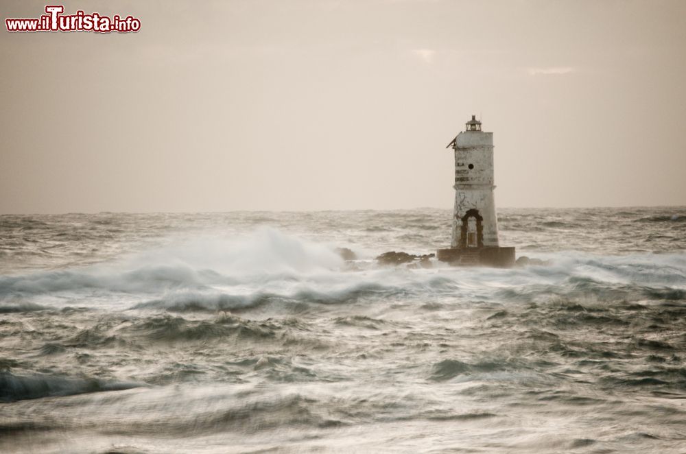 Immagine Faro di Mangiabarche a Calasetta con il mare in burrasca (Sardegna). Su un piccolo scoglio che sorge davanti alla spiaggia di Mangiabarche s'innalza un faro solitario che ha il compito di evitare che le imbarcazioni s'incaglino nelle rocce affioranti.