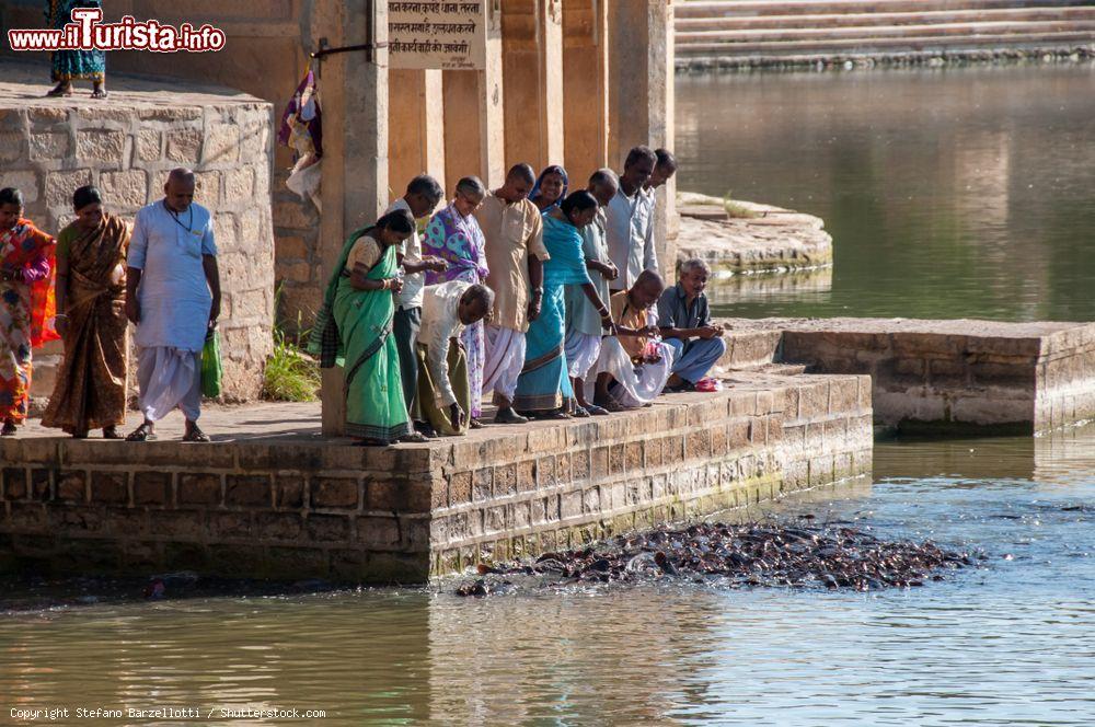 Immagine Fedeli cibano centinaia di pescegatto nel lago artificiale Gadi Sahar Tank a Jaisalmer, Rajasthan, India - © Stefano Barzellotti / Shutterstock.com