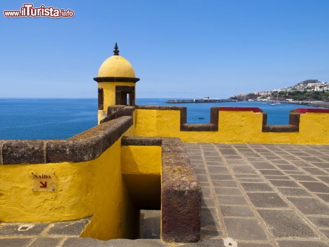 Immagine Il Forte Sao Tiago a Madeira (Portogallo) - Non solo è la sede del Museo dell'Arte Contemporanea, ma è anche il castello più stravagante di Funchal. Quello che colpisce immediatamente è il suo colore: un giallo così vivo e così acceso, che soprattutto nelle giornate di sole, riesce ad abbracciare tutto il panorama. Al suo interno vi è un ristorante. Vi si accede dalla passeggiata di Santa Maria e sul bellissimo terrazzo, come si può vedere dall'immagine, la vista sull'oceano atlantico regala uno spettacolo unico - © Petroos / Shutterstock.com