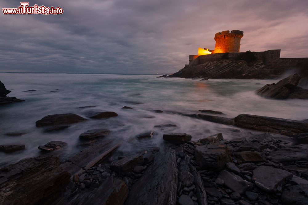 Immagine Una piccola fortezza illuminata di notte a Socoa nella baia di Donibane Lohitzune a Saint-Jean-de-Luz, Francia. In primo piano, l'Oceano Atlantico.