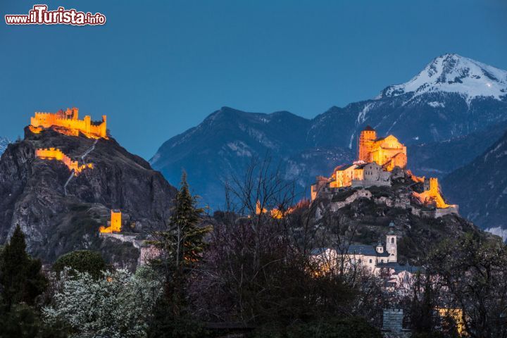 Immagine Una bella immagine notturna del castello di Tourbillon e di quello di Valère. Per raggiungere il primo, in rovina a causa di un incendio che nel 1788 lo distrusse in gran parte, bisogna affrontare una lunga camminata per poter ammirare le splendide vedute che si godono sulla città. Il secondo racchiude una basilica del XII° secolo con all'interno il più antico organo funzionante al mondo che sporge dal muro di fronte all'abside come la poppoa di una caravella medievale. Dalla basilica si può osservare un suggestivo panorama che abbraccia l'intera città  - © l i g h t p o e t / Shutterstock.com