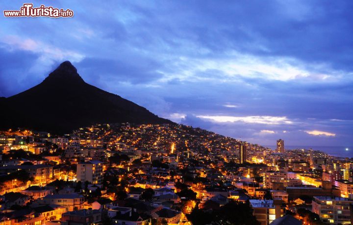 Immagine Fotografia notturna di Città del Capo, Africa del Sud - Se quando c'è il sole la Città del Capo si tinge di tinte calde e tenui, quando arriva l'ora notturna non lascia meno stupore. Come si vede dall'immagine, vista dall'alto di notte, lascia senza fiato, soprattutto perché la montagna regala quel tocco di onirico che non si trova in altre mete. Così superba e imponente, sembra un vero e proprio invito a vivere la località o comunque a sognarla con gli occhi ben aperti - © littlewormy / Shutterstock.com