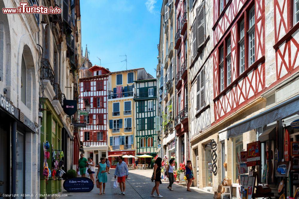 Immagine Gente a passeggio in una strada di Bayonne, Francia, in una giornata di sole. Addossate le une alle altre, le case alte di Bayonne con le persiane colorate creano un insieme molto caratteristico - © Allen.G / Shutterstock.com