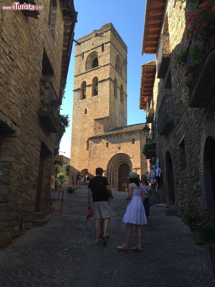 Immagine Gente a passeggio nel centro storico di Ainsa con il campanile sullo sfondo, Pirenei, Spagna. Ancora oggi le stradicciole e gli antichi edifici di questo borgo spagnolo raccontano le storie più affascinanti del suo periodo medievale.