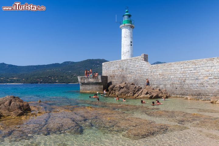 Immagine Gente al mare nei pressi della spiaggia di Propriano, Corsica. Sullo sfondo, il faro della città che si affaccia sul Golfo di Valico - © Eugene Sergeev / Shutterstock.com