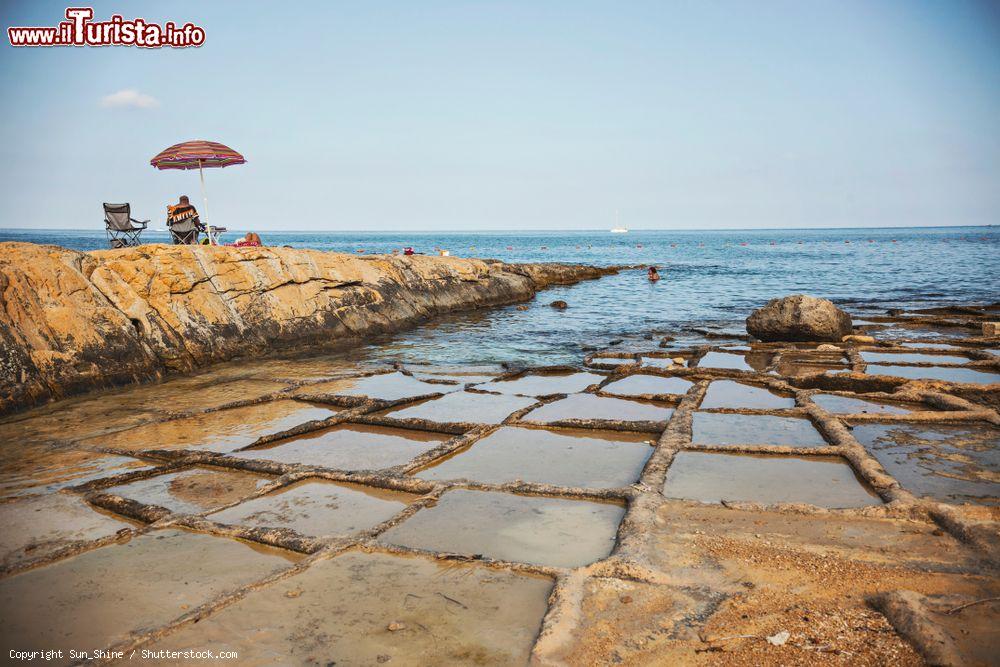 Immagine Gente in relax nei pressi di Zonqor Point Salt Pans a Marsascala, Malta. Si tratta di una serie di piscine naturali scolpite dalle onde del mare  - © Sun_Shine / Shutterstock.com