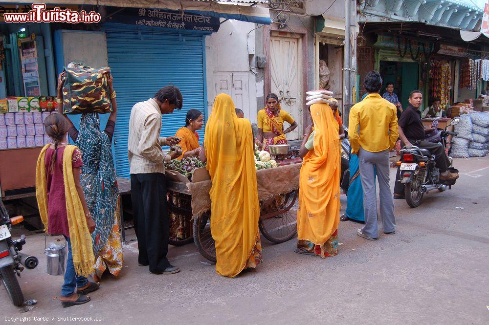 Immagine Gente in una strada di Udaipur, Rajasthan, India. Donne con gli abiti colorati fanno shopping in una bancarella lungo una via del centro - © CarGe / Shutterstock.com