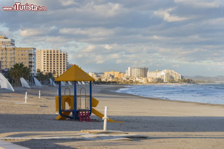 Immagine Giochi per i bambini sulla spiaggia di Morro de Gos a Oropesa del Mar, Spagna. Sullo sfondo i palazzi moderni che si affacciano sul lungomare di questa ridente città della Comunità Autonoma Valenciana