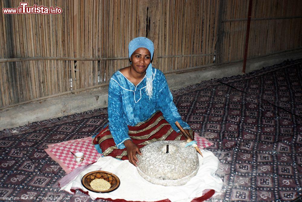 Immagine Una giovane donna beduina di Douz (Tunisia) indossa abiti tradizionali e macina il grano a mano - © meunierd / Shutterstock.com