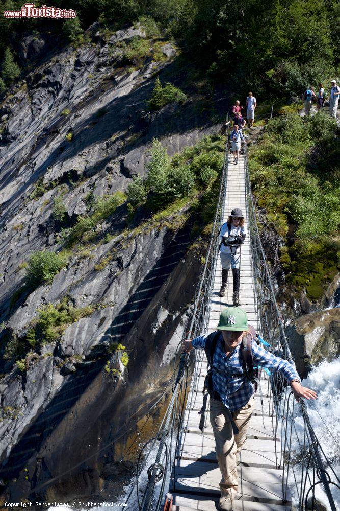 Immagine Giovani escursionisti attraversano un ponte sospeso sul torrente a Saint-Gervais-les-Bains, Francia. Siamo nell'area del ghiacciaio di Bionnassey - © Senderistas / Shutterstock.com